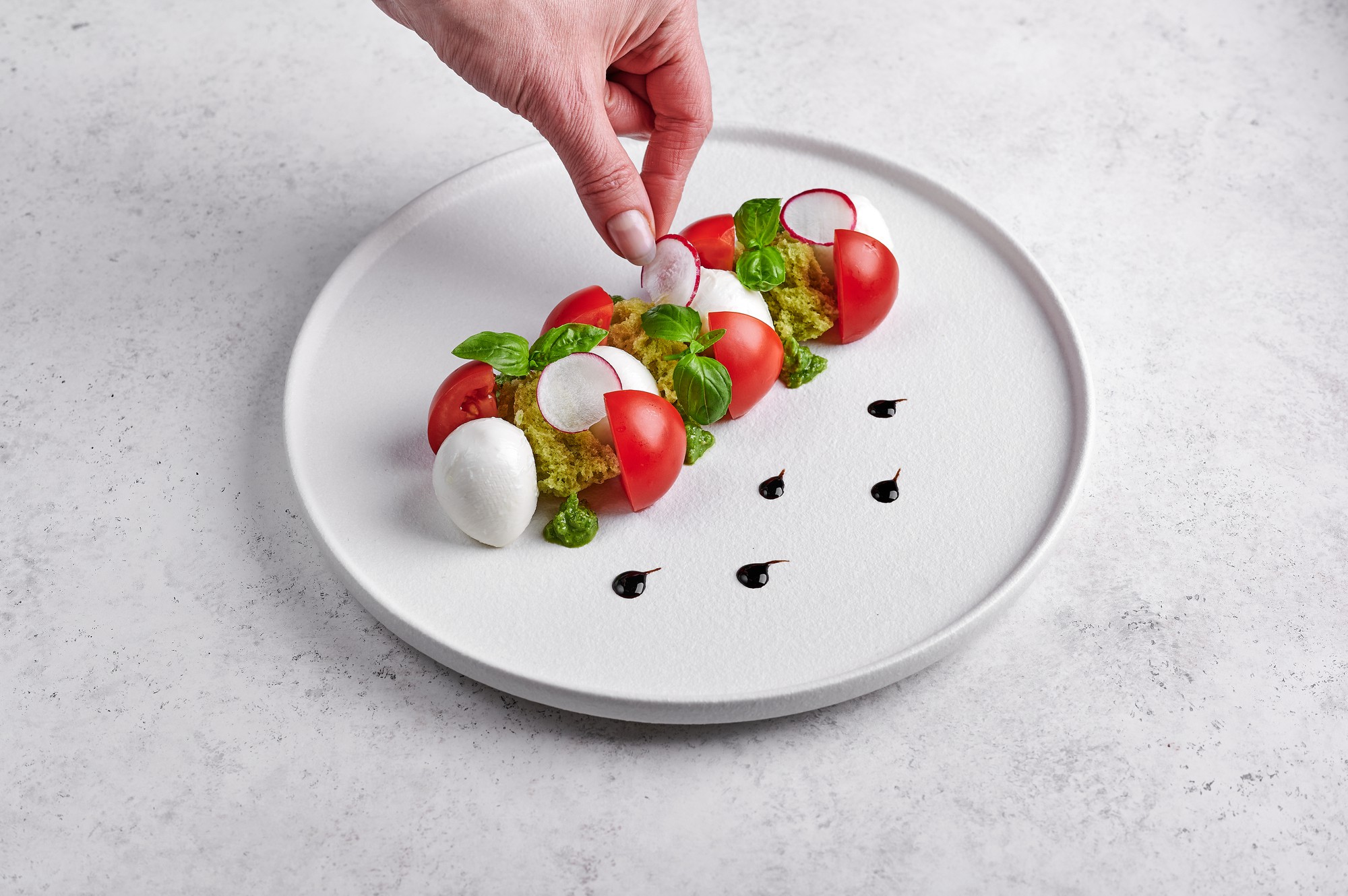 Hands arranging plated dish in modern kitchen