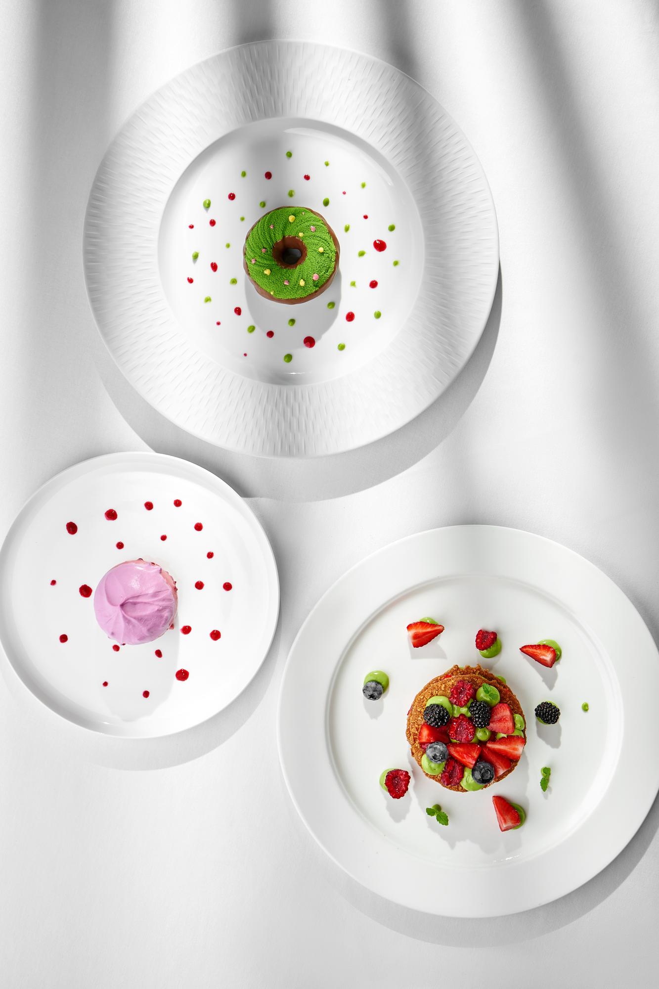 Three sample plated dishes in neutral studio